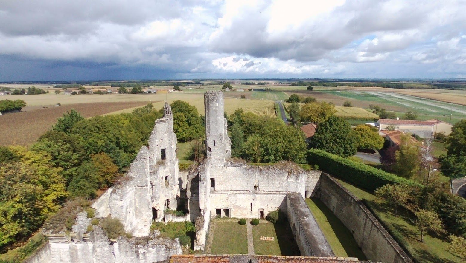 Vue depuis le châtelet vers la haute cour : haute tour ruinée, murs de la demeure des Bohier, mur d'enceinte avec couloir, douve à droite.