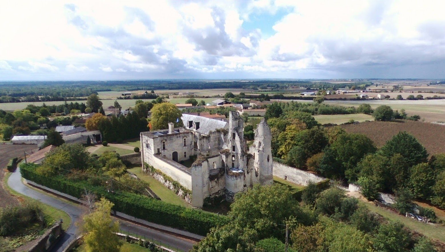 Vue aérienne du château depuis le sud-est : châtelet, ruines et long bâtiment entourés de la douve.