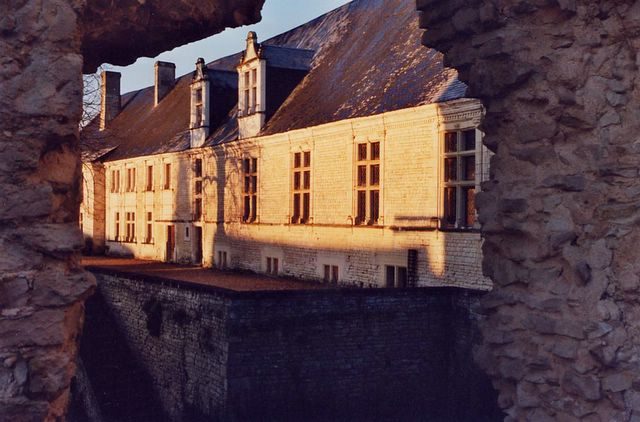 Le long bâtiment vu d'en bas, posé sur un haut mur de gros blocs dominant le fossé.